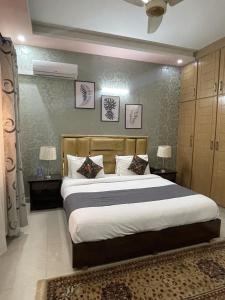 Safari Hotel في اسلام اباد: غرفة نوم بسرير كبير مع طاولتين ومصباحين