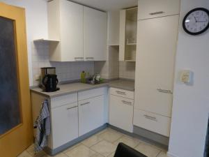 Una cocina con gabinetes blancos y un reloj en la pared. en Ferienwohnung Schön, en Münchenbernsdorf