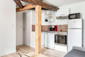 a kitchen with white cabinets and a brick wall at Nationale 202 CahorsCityStay in Cahors +6 photos