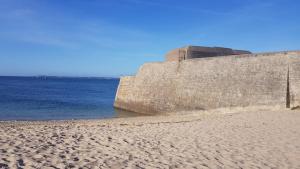 uma praia de areia junto a uma parede de pedra junto à água em APPARTEMENT PRES DE LA MER AVEC GRANDE TERRASSE em Riantec