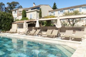 a pool with chairs and umbrellas next to a building at Hôtel Le Pré Saint Michel in Manosque