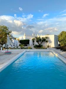 einem Pool mit blauem Wasser vor einem weißen Gebäude in der Unterkunft VITA VIVET TRULLO in San Michele Salentino