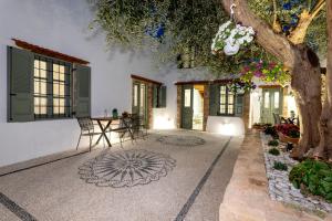 une cour avec une table, des chaises et un arbre dans l'établissement Villa del Capo Suites, à Rhodes
