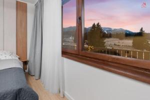 a bedroom with a window with a mountain view at Albert Residence Grand Chalet & SPA Poiana Brașov in Poiana Brasov