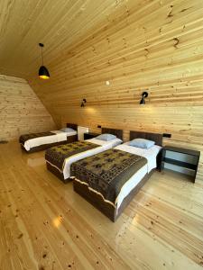 three beds in a room with a wooden wall at Cottage Eco house in Kobuleti