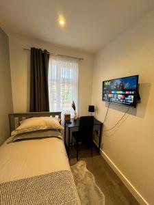 a bedroom with a bed and a desk with a tv on the wall at Gorgeous Budget Room in Beckenham