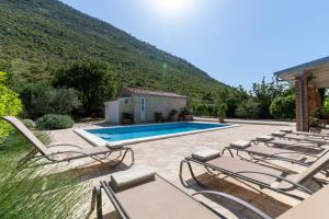 a villa with a swimming pool and lounge chairs at House with pool Garden in Žrnovnica