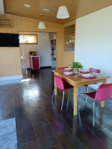 ein Esszimmer mit einem Holztisch und rosa Stühlen in der Unterkunft La Casita de Mari in Moaña