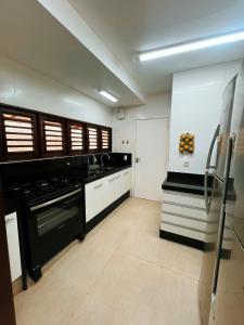 een keuken met zwarte apparaten en witte kasten bij Casa Sonho da praia beira-mar 04 suítes in Barra de Santo Antônio