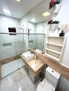 een badkamer met een wastafel, een toilet en een spiegel bij Casa Sonho da praia beira-mar 04 suítes in Barra de Santo Antônio