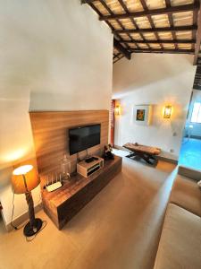 een woonkamer met een televisie en een bank bij Casa Sonho da praia beira-mar 04 suítes in Barra de Santo Antônio
