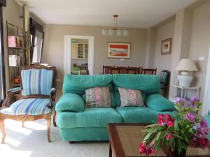 a living room with a green couch and a chair at Chalet en la playa, vistas al mar in Pobra do Caramiñal