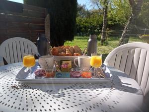 una bandeja de comida en una mesa con zumo de naranja y pan en La Canette de Phil - Chambre d'hôtes - Hébergement indépendant - vue sur piscine, en Samatan