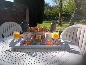 uma bandeja de comida numa mesa com sumo de laranja e pão em La Canette de Phil - Chambre d'hôtes - Hébergement indépendant - vue sur piscine em Samatan