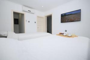 Duas camas num quarto branco com uma televisão na parede em וילת פאר בקו ראשון לים em Ashdod