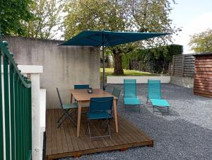 a wooden table with chairs and an umbrella at gite du puits in Bernières-dʼAilly