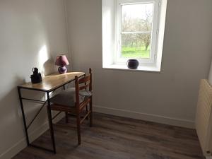 a table with a lamp and a chair in front of a window at gite du puits in Bernières-dʼAilly +5 photos
