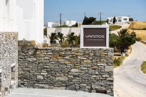 een bord op een stenen muur naast een weg bij Vammos Luxury Apartments in Naousa