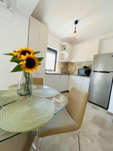 a kitchen with a glass table and a vase with a sunflower at Holidays Makerel Lodge Vibes Mamaia Nord in Mamaia Nord