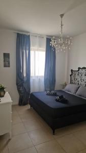 a bedroom with a bed with blue curtains and a chandelier at St Julian's Central Paceville Apartments in St Julian's