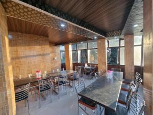 uma sala de jantar com mesas, cadeiras e janelas em Jungle Stay Dalhousie(Kalatop) em Dalhousie