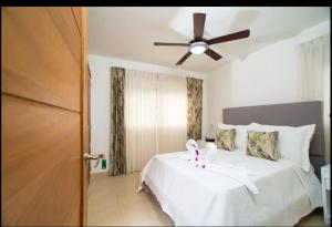 a bedroom with a white bed with a ceiling fan at Cristamar Condominium "Cozy Oasis, Adorable" in Cabarete