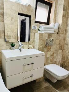 a bathroom with a sink and a toilet and a mirror at Holidays Makerel Lodge Vibes Mamaia Nord in Mamaia Nord