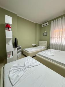 um quarto com duas camas e uma tv nele em Solei Apartments em Saranda
