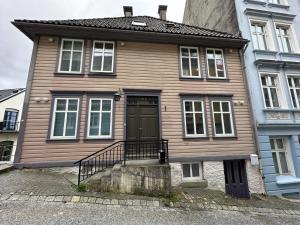 una casa de madera con una puerta negra en una calle en Sjarmerende bolig like ved togstasjonen, en Bergen