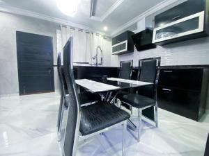 a dining room with a table and black chairs at IRISH Apartment in Kasoa
