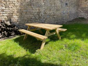 een houten picknicktafel in het gras naast een bakstenen muur bij Aux Fleurs de Darcy Confort Centre Ville in Dijon