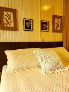 a bedroom with a white bed with pictures on the wall at Casa da Vó Hospedagem Afetiva in Bento Gonçalves