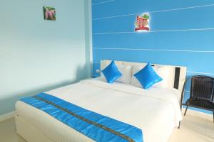een blauwe slaapkamer met een wit bed met blauwe kussens bij Phuket Andaman Place ภูเก็ตอันดามันเพลส in Phuket