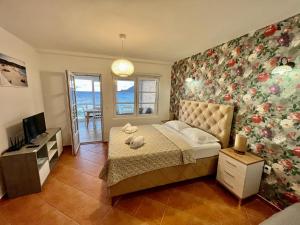 1 dormitorio con 1 cama con pared de flores en Apartments AriaSana, en Dobra Voda