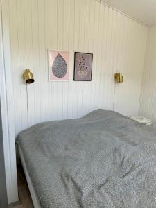 LøgstrupにあるBeautiful summerhouse with full View of the fjordのベッドルーム1室(ベッド1台付)が備わります。壁に3枚の写真が飾られています。