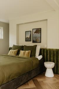 een slaapkamer met een groen bed en een tafel bij B&B Sur Place in Huizen