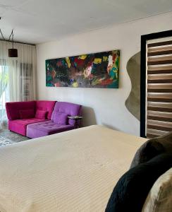 ein Schlafzimmer mit einem Bett und einem lila Sofa in der Unterkunft THUISHAVEN boutique mini-resort - fantastic garden and large pool - adults only in Willemstad