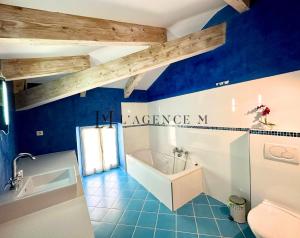 a blue bathroom with a tub and a sink at Bella Vista - Duplex d'exception avec terrasse suspendue et vue panoramique sur la baie de Calvi in Lumio +17 photos