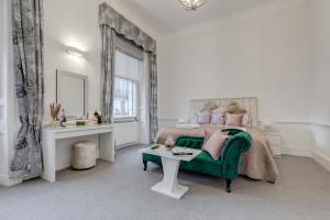 a bedroom with a bed with a green chair and a table at Stylish 3 Bedroom Luxury Apartment in Harley St 3 in London