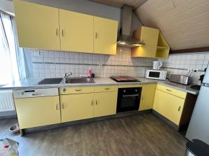 uma cozinha com armários amarelos e um lavatório em Le DaubenLand em Daubensand