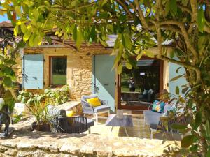 a patio with chairs and a table under a tree at Larroque Haute Gites in Cassagnes