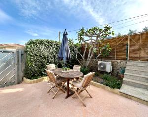 uma mesa e cadeiras com um guarda-sol num pátio em Appartement Saint-Antoine, paisible em Calvi