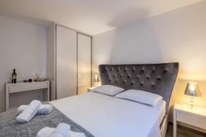 a bedroom with a white bed with a black headboard at Luxury Apartment Anna in Split