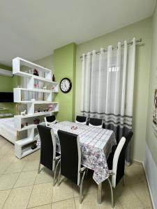 uma sala de jantar com mesa e cadeiras e um relógio em Solei Apartments em Saranda