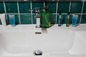 Un lavabo de baño con una botella verde y cepillos de dientes. en Residenza Palazzo Miraldi-Ferrari, en Cava deʼ Tirreni