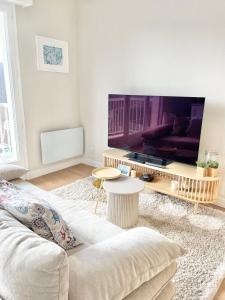 uma sala de estar com um sofá e uma grande televisão em Appartement avec Balcon et place de Parking à Berck Plage em Berck