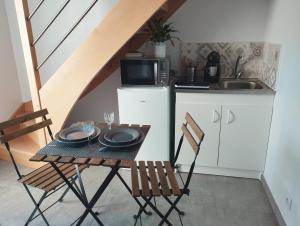 eine kleine Küche mit einem Tisch, Stühlen und einer Mikrowelle in der Unterkunft Location Logement Au Cœur du Vignoble et Spa in La Chapelle-Heulin