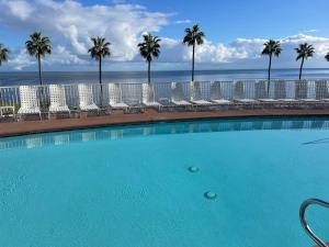 a swimming pool with chairs and palm trees and the ocean at Catalina Island Getaway With New 6 Seat Golf Cart in Avalon