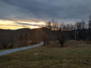 una carretera en un campo con la puesta de sol en el fondo en Adirondack Retreat, en Bakers Mills