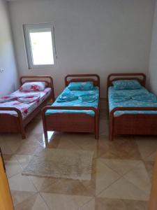 three twin beds in a room with a window at Bujtina Aliaj in Tropojë
